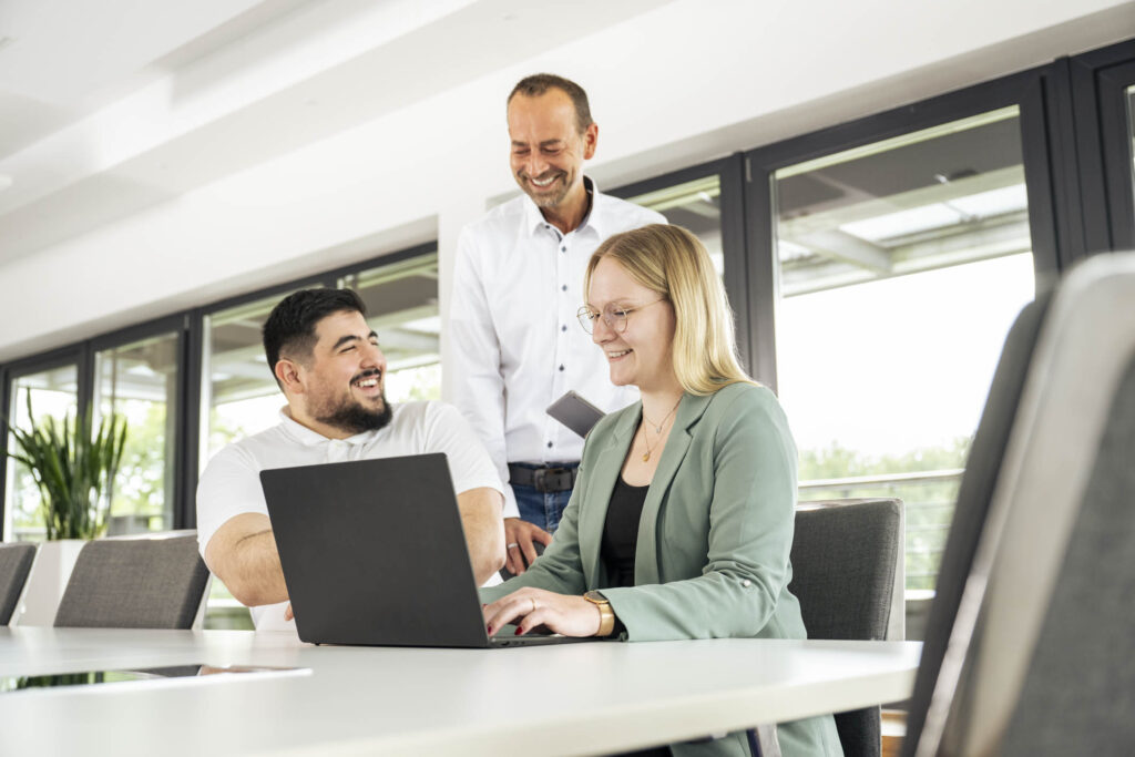 Drei Personen sitzen gemeinsam vor einem Laptop